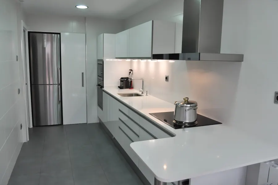 Cocina blanca con península, campana de acero y frigorífico integrado