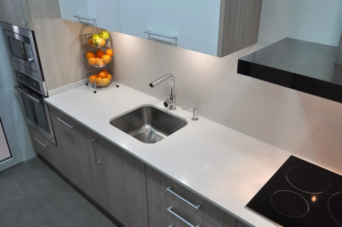 Cocina con encimera clara, fregadero de acero y placa de inducción