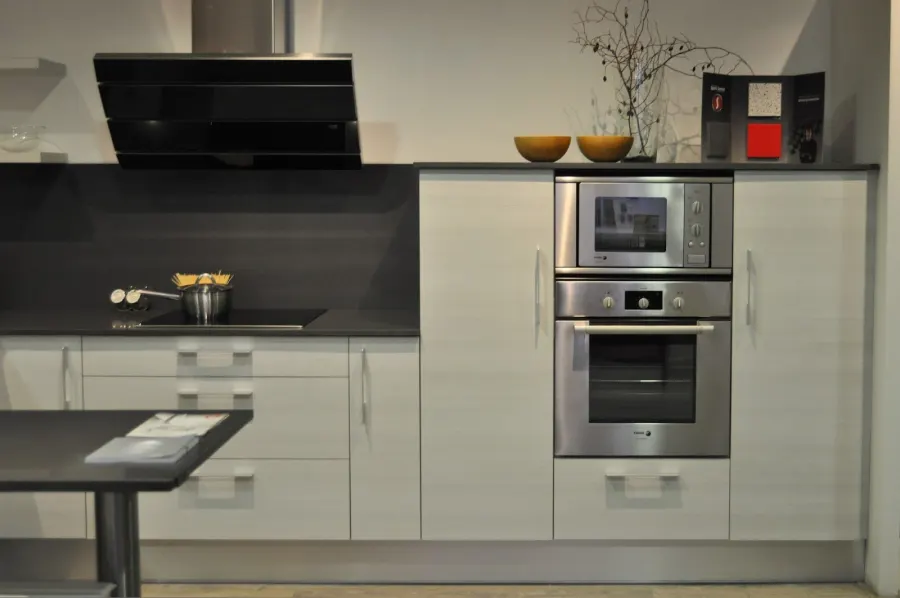 Cocina blanca con frente gris oscuro, horno y microondas en columna