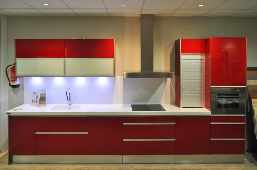 Cocina con muebles rojos brillantes y encimera blanca